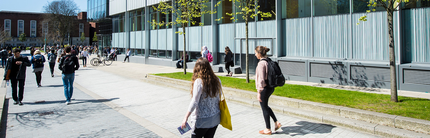 Students walking outside the Alan Gilbert Learning Commons on a sunny day.