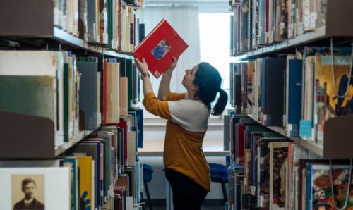 Person taking book off shelf in Library 