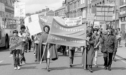 Black and white photograph of protestors holding 'No deportation for Cynthia Gordon!' banner