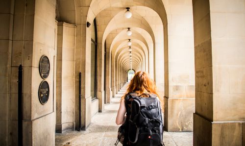 Photo: Woman looking through the arches outside Manchester Central Library