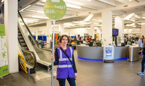 Staff member holding 'here to help' sign in Main Library