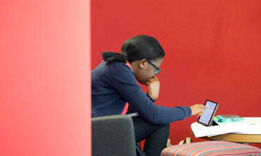 Student reading an etextbook on a tablet in the library.