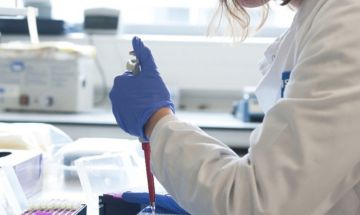 A close view of a researcher's hand in a lab using a pipette