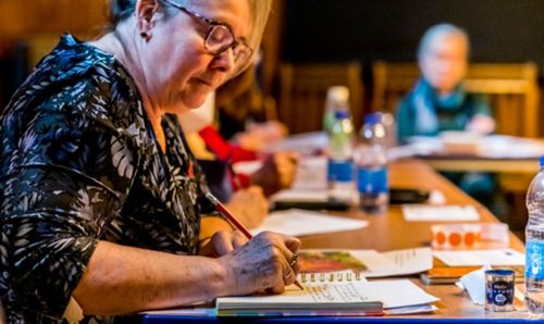 A woman working at a laptop surrounded by others in a room at the Rylands