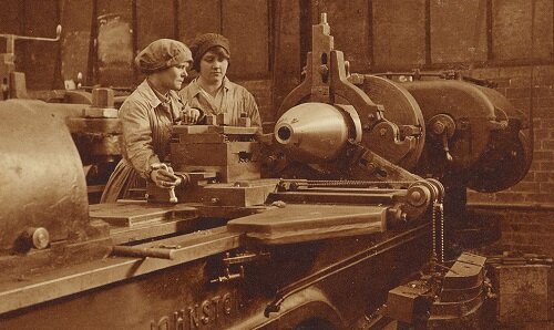 Two women working on an industrial lathe making 11-inch artillery shells