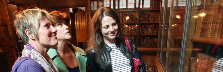 Three visitors admiring an exhibit in Rylands