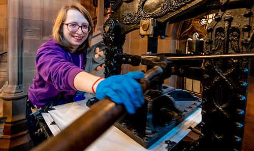 Hands inking metal type ready for printing.