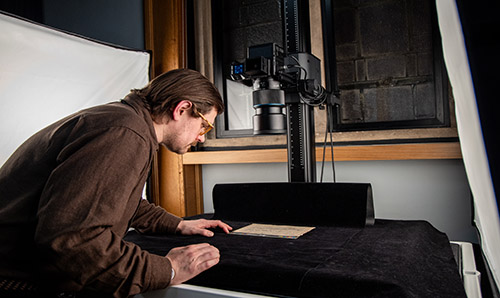 Man using a camera and copy stand set up to photograph an item from the collections