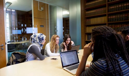 Student sitting around a desk in one of the Green 2 meeting rooms in Main Library
