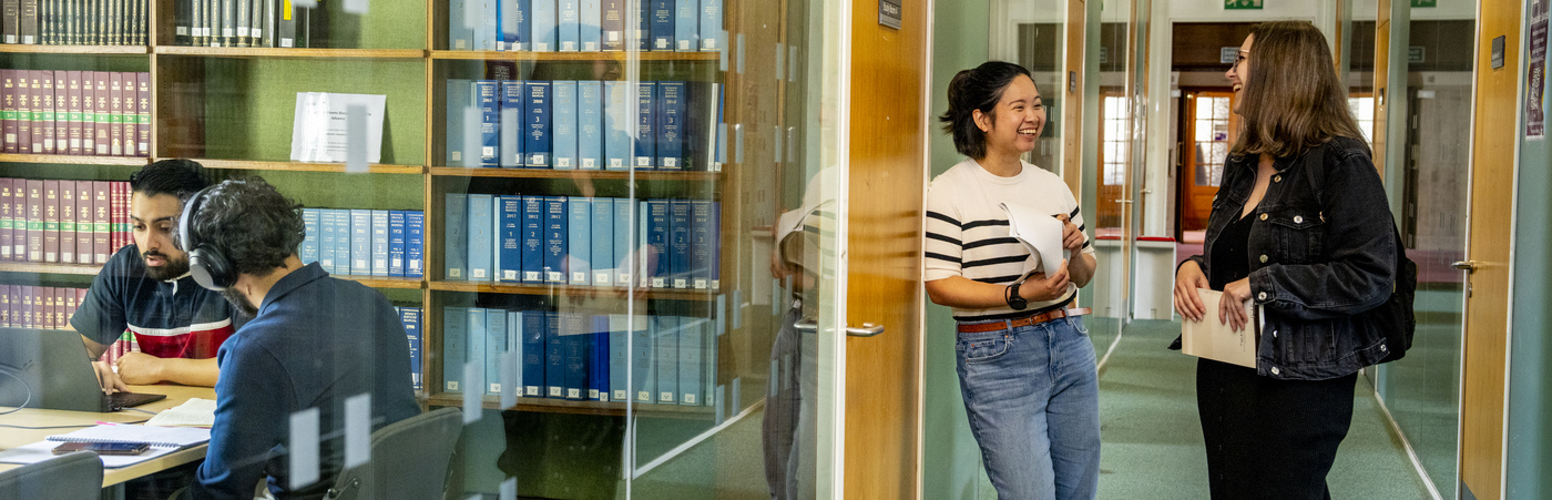 Two Library users chatting in Green 2 zone in Main Library while others work in the group study rooms