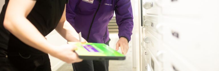 A member of Library staff assisting a student with a laptop loan