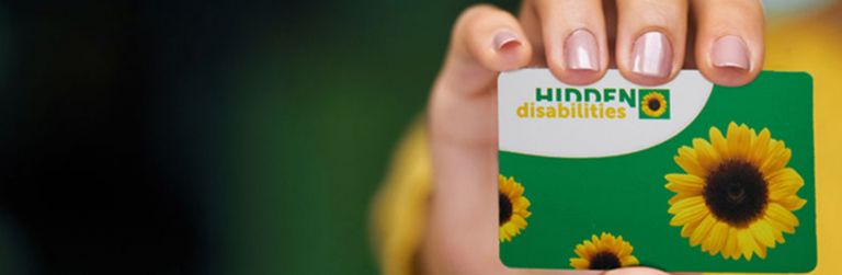 Close up shot of a hand holding a card that reads Hidden Disabilities