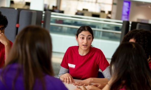 A student team member in a red University of Manchester t-shirt speaking 